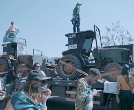 lidé s brazilskými vlajkami pochodují podél vozu vezoucím traktory
