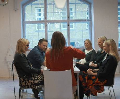 skupina lidí sedících kolem stolu si povídá