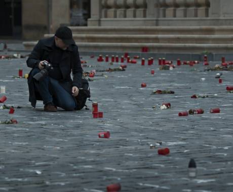 muž s kamerou uprostřed náměstí, které je pokryté svíčkami